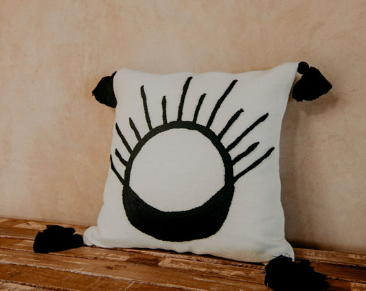Hand-loomed pillow and embroidered by skilled artisans with an abstract design stitched on a white ground finished with black pom poms