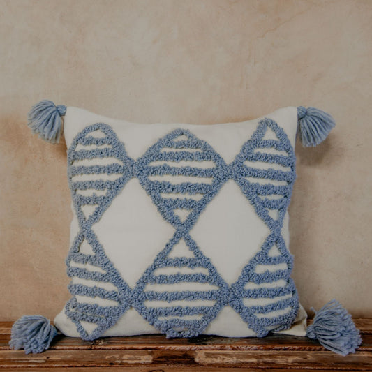 Wool yarn stitches up a textured pillow, while the geometric diamond patterns add an intriguing touch and the pom-poms add a playful feel.