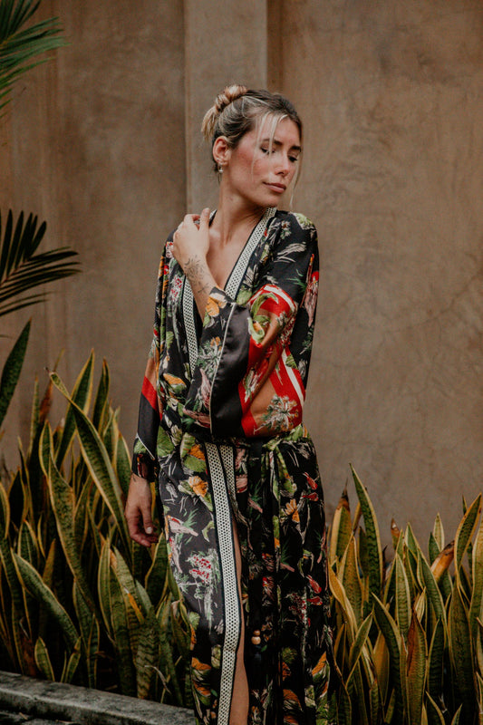 This silky kimono with wide sleeves is gorgeous. We love the combination of flower and bird prints that grant an imperial vibe to this kimono. The neckline is enhanced by an elegant handwoven silk trim.