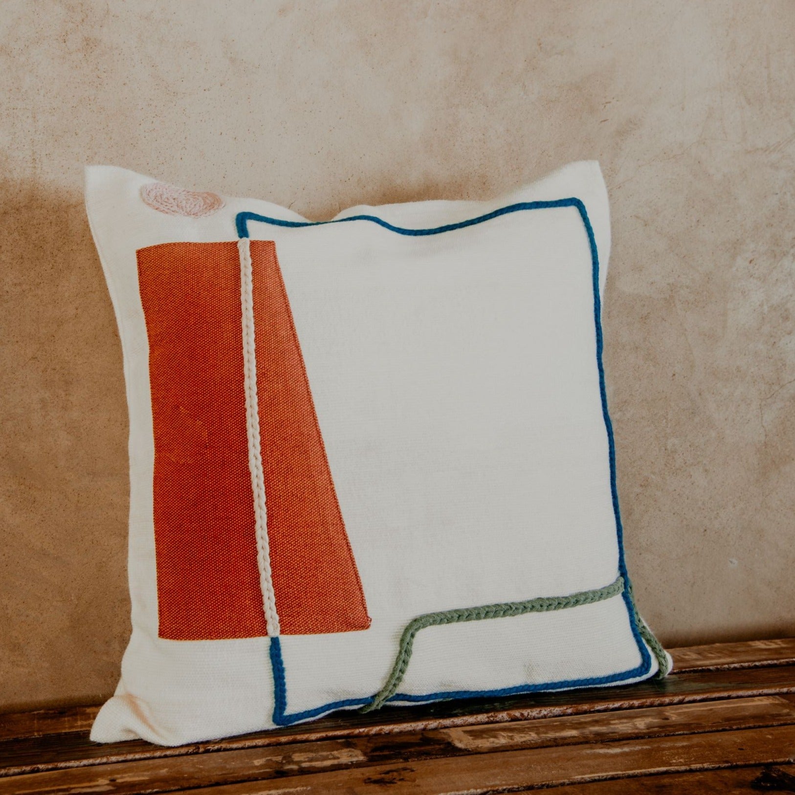 Asymmetric and colourful wool designs float across the ivory space of this beautiful pillow. Hand-loomed by expert artisans, the different shapes embroidered in wool bring an artsy look and extra coziness to your bed, sofa or chaise.