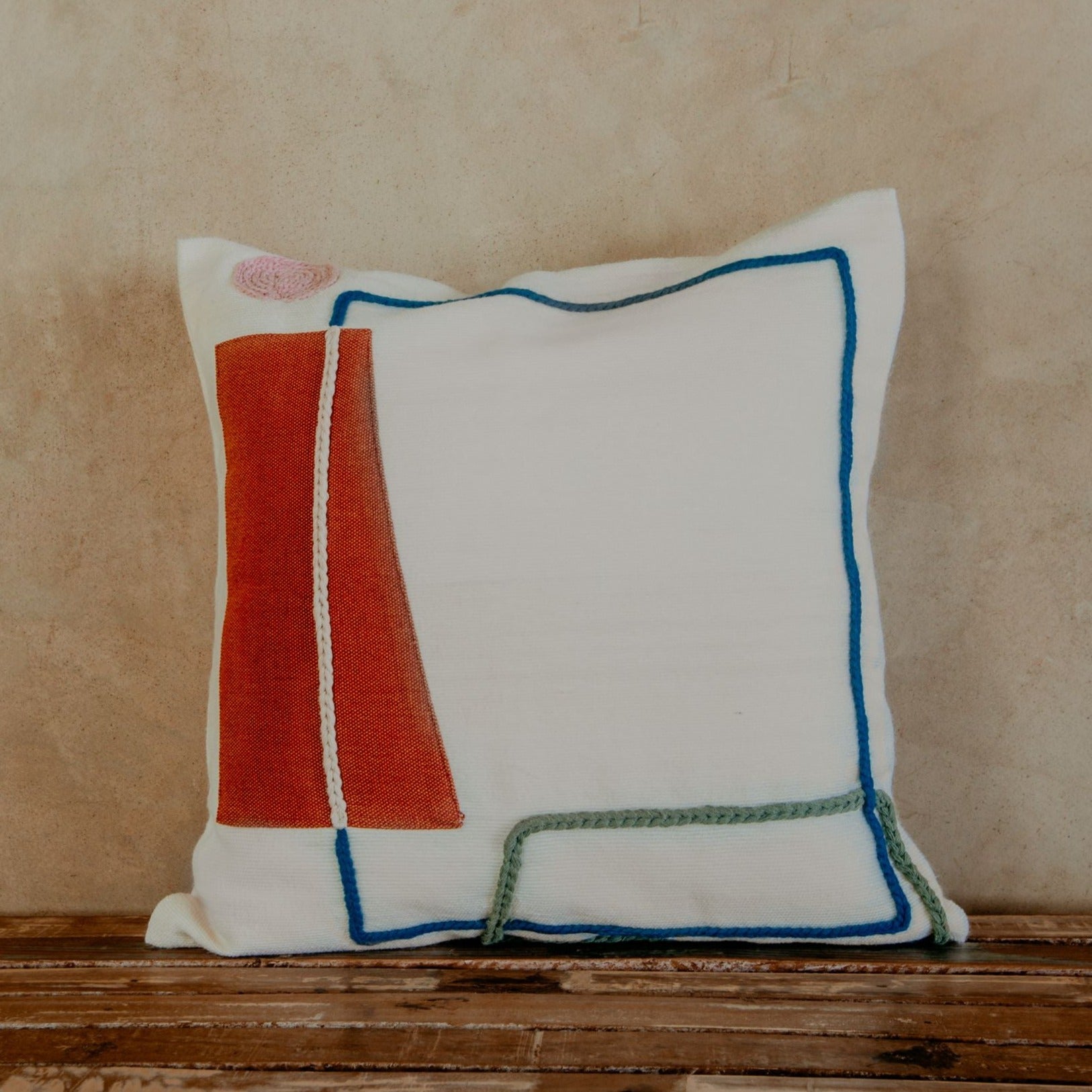 Asymmetric and colourful wool designs float across the ivory space of this beautiful pillow. Hand-loomed by expert artisans, the different shapes embroidered in wool bring an artsy look and extra coziness to your bed, sofa or chaise.