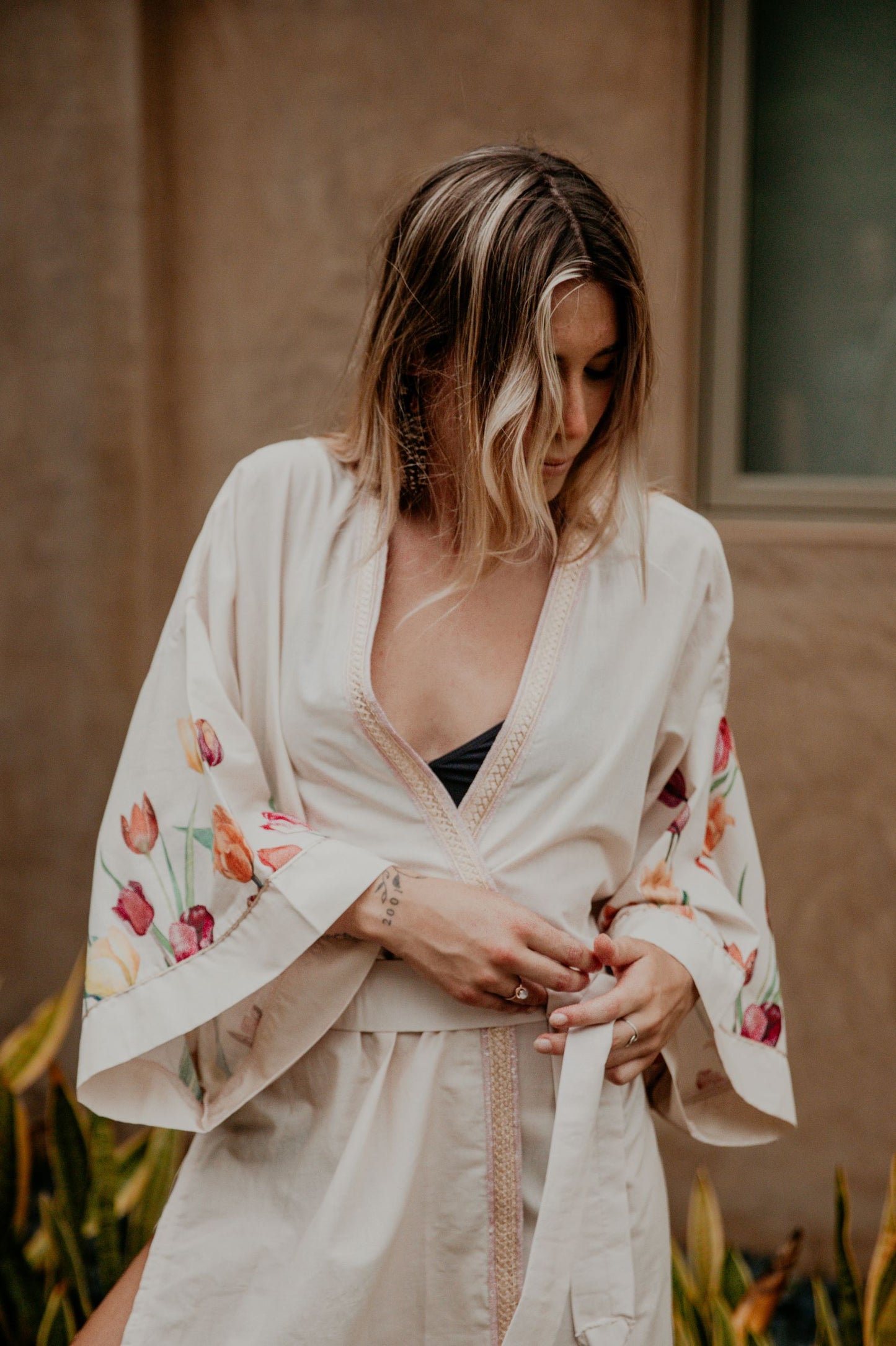 This heavenly pink flowery kimono is gorgeous. We love the sassy side slits and the wide sleeves embellished with a golden thread. The neckline is enhanced by an elegant handwoven silk trim.  The waist is sublimated by a beautiful long belt finished with Moroccan handmade tassels with vegetal silk threads and natural stones.