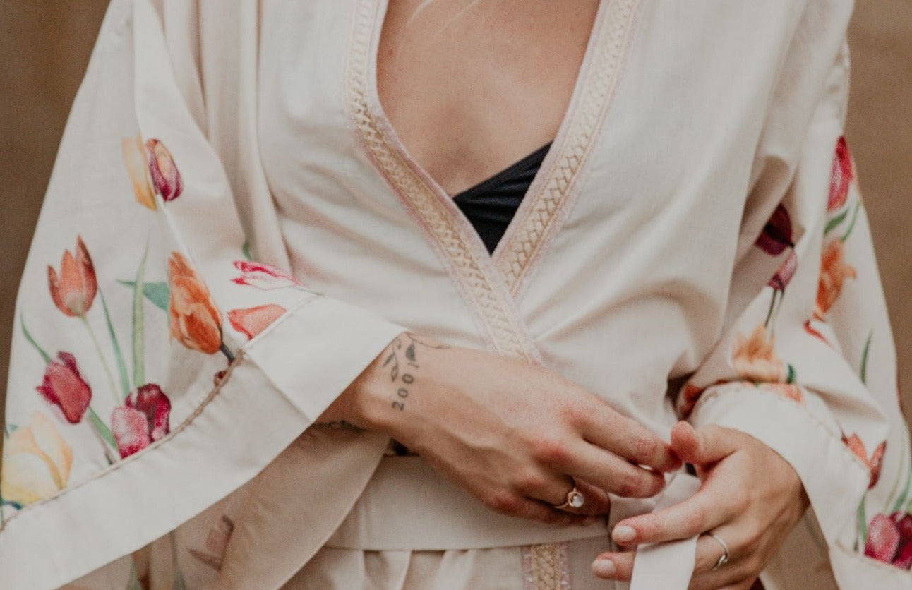 This heavenly pink flowery kimono is gorgeous. We love the sassy side slits and the wide sleeves embellished with a golden thread. The neckline is enhanced by an elegant handwoven silk trim.