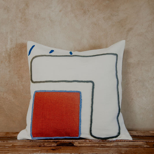 Asymmetric and colourful wool designs float across the ivory space of this beautiful pillow. Hand-loomed by expert artisans, the different shapes embroidered in wool bring an artsy look and extra coziness to your bed, sofa or chaise.