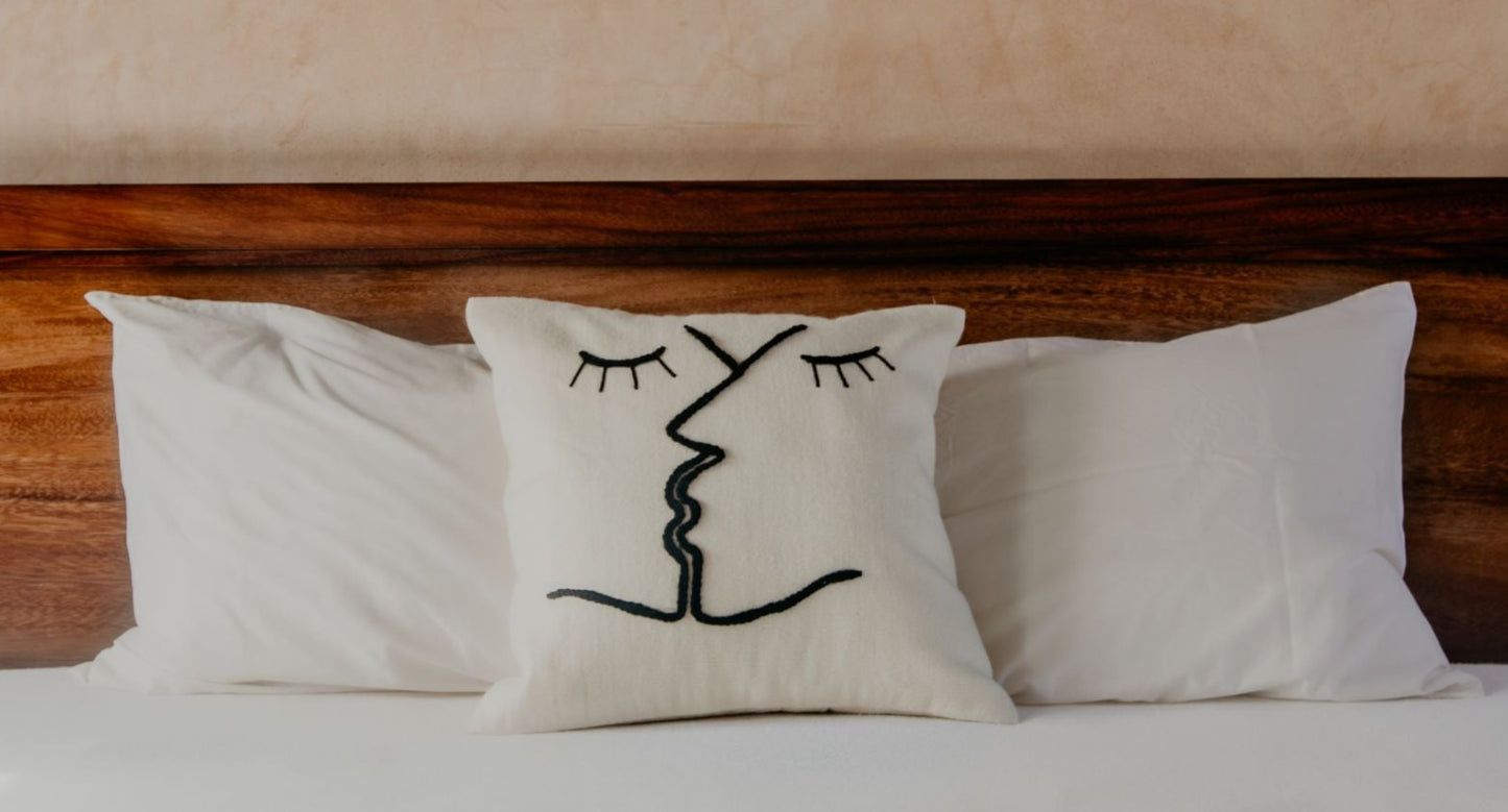 You will love this look-good, feel-good pillow. Hand-loomed and embroidered by skilled artisans with two kissing faces stitched on a cream ground