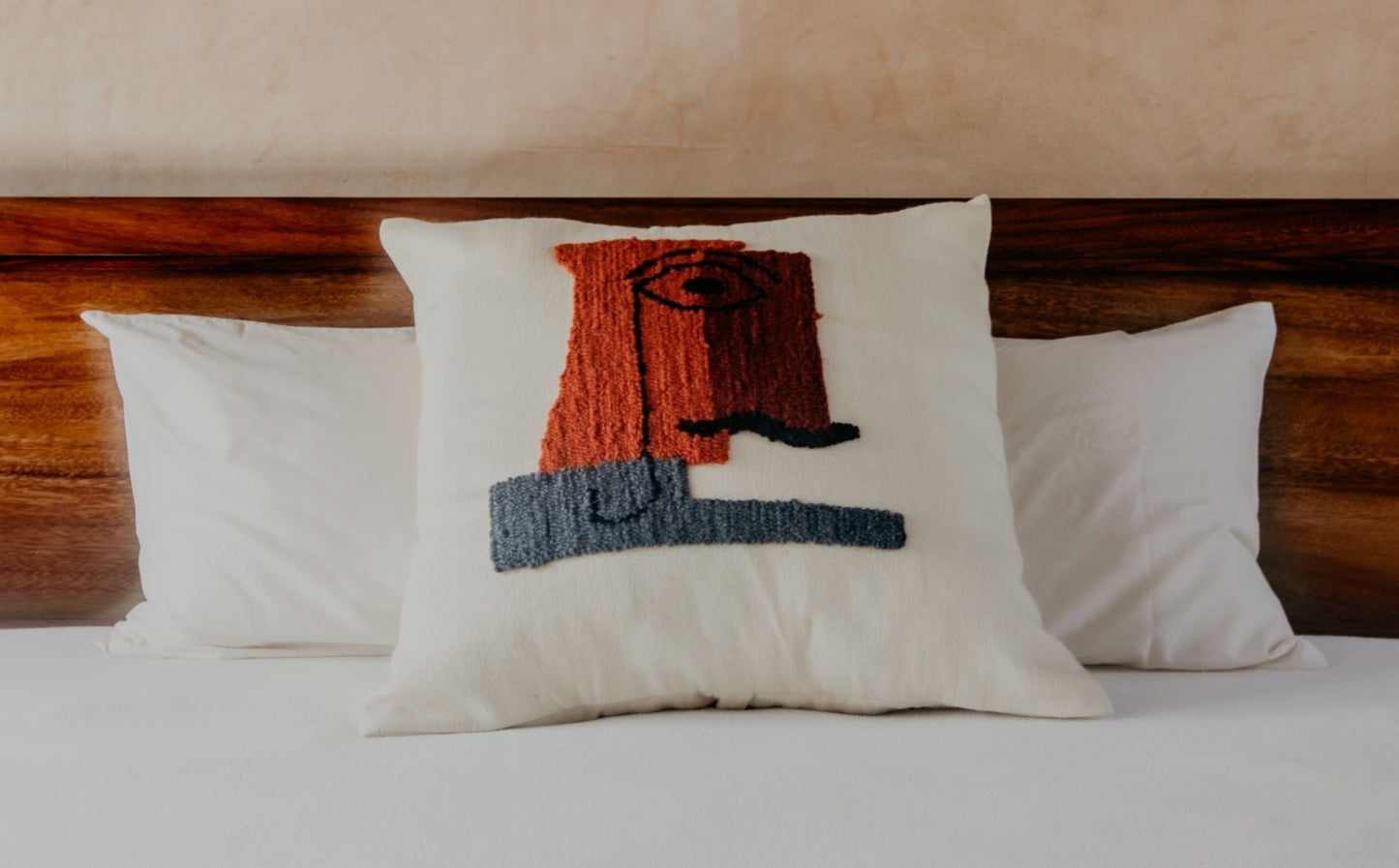 Asymmetric and colourful wool designs float across the cream space of this beautiful pillow to create an elegant man's face from another century.